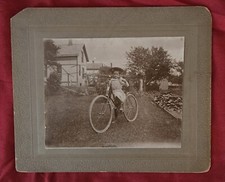 1901 Menina em uma bicicleta no quintal, casas antigas ao fundo comprar usado  Enviando para Brazil