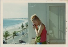 Mulher com câmera na varanda sobre praia tropical, 1969 comprar usado  Enviando para Brazil