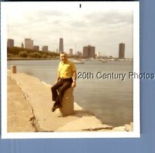 FOTO COLORIDA ENCONTRADA I+7380 HOMEM POSANDO SENTADO EM BLOCO DE CONCRETO PELA ÁGUA, PARTE DE TRÁS DA CIDADE comprar usado  Enviando para Brazil