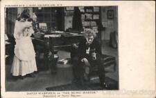 Teatro Un hombre sentado en un banco de piano leyendo un mampleto y una mujer de pie be segunda mano  Embacar hacia Argentina