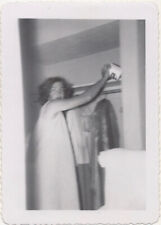 Mujer en camisón alcanzando papel higiénico en estante armario superior, años 40 segunda mano  Embacar hacia Argentina