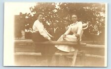 Pocztówka 2 mężczyzn i 2 kobiety siedzące/stojące przy drewnianych słupkach ogrodzeniowych RPPC G98 na sprzedaż  Wysyłka do Poland